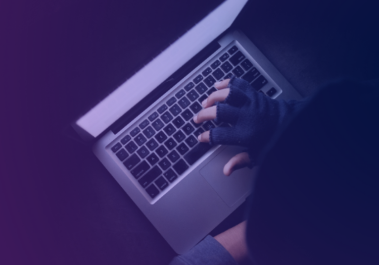 cyber criminal on a laptop with a glove on their hand