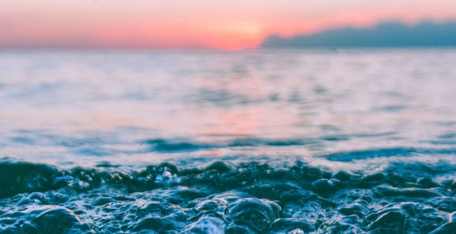 closeup of ocean with pastel sunset